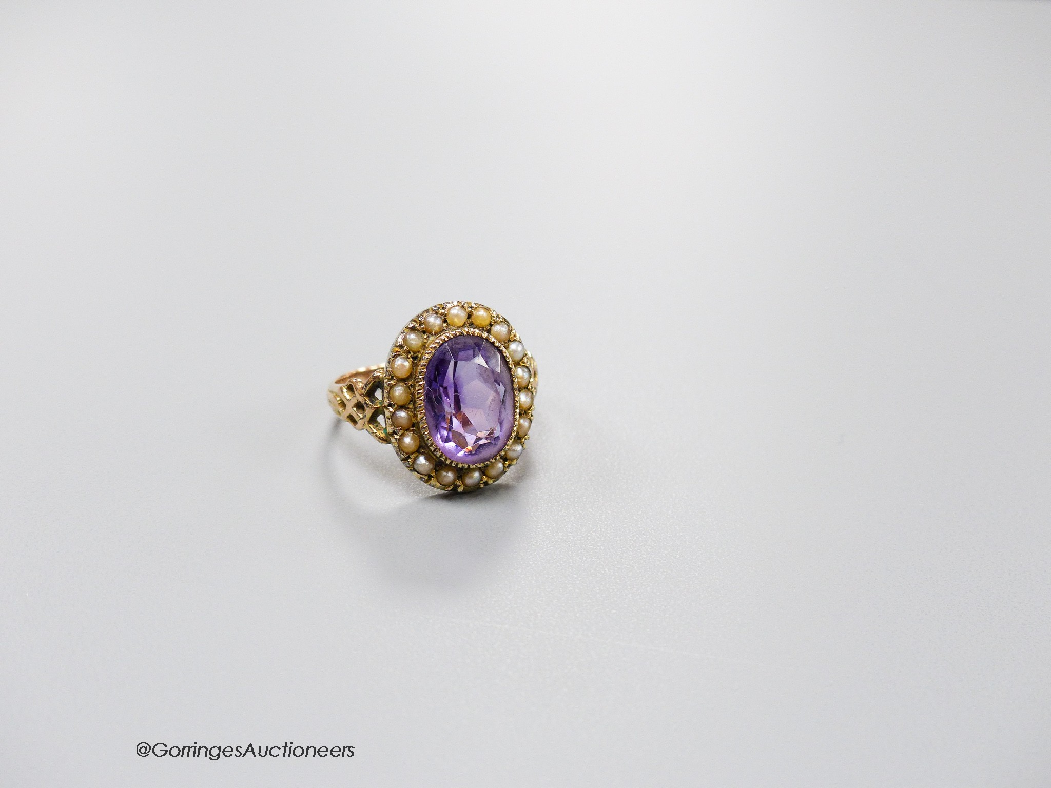 A 19th century yellow metal, amethyst and seed pearl set oval cluster dress ring, size N, gross 3.8 grams.